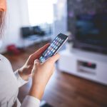 Kvinne som bruker mobilen i stuen